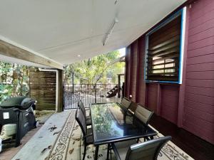 a screened porch with a glass table and chairs at Tropical Cabin Retreat in Mission Beach