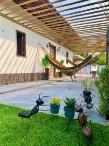 a hammock in a yard with some statues of bugs at L2 Localize casa na praia pontal in Fortim