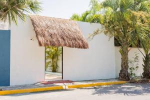 a white building with a thatched roof and palm trees at M&Z Loft Las Palmas in Cancún