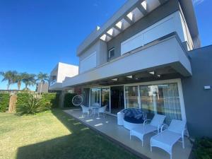 a house with a patio with chairs and a table at Casa Luxuosa no Condomínio Villaggio Atlântida in Xangri-lá