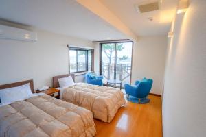 a hotel room with two beds and blue chairs at Marine Blue Yakushima in Yakushima