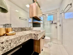 a bathroom with a sink and a toilet and a shower at Apartamento Luxuoso de 2 Dormitórios in Capão da Canoa