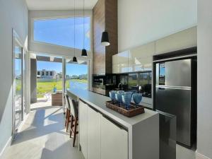 eine Küche mit einer Theke mit Stühlen und einem Kühlschrank in der Unterkunft Casa Luxuosa no Condomínio Ilhas Resort in Capão da Canoa