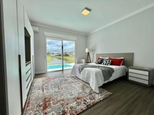 ein Schlafzimmer mit einem Bett, einem TV und einem Pool in der Unterkunft Casa Luxuosa no Condomínio Ilhas Resort in Capão da Canoa