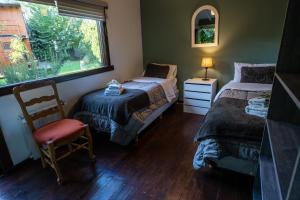 a bedroom with two beds and a chair and a window at Casas Huron!! in San Carlos de Bariloche