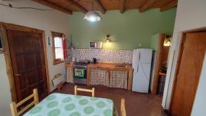 Una cocina con una mesa y un refrigerador blanco. en Cabañas Mónika IV Sur, en Huerta Grande