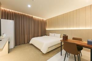 1 dormitorio con cama blanca, escritorio y escritorio en Daegu Hotel Series Lions Park, en Daegu