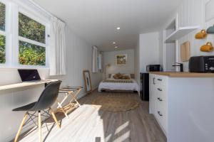 a kitchen with a desk and a bedroom with a bed at Otaki Beach Guesthouse in Otaki Beach