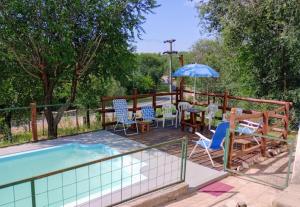 a pool with chairs and a table and an umbrella at Altos del Peñón Cabañas in Casa Grande