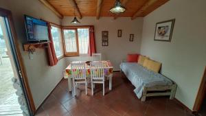 a room with a bed and a table with chairs at Cabañas Mónika III Norte in Huerta Grande