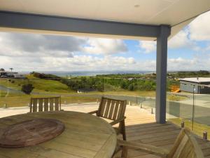 a wooden table and chairs on a deck with a view at Karikari Vista in Karikari Peninsula