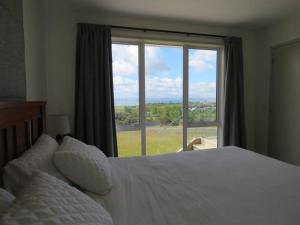 a bedroom with a bed and a large window at Karikari Vista in Karikari Peninsula +12 photos