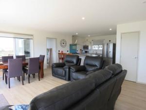 a living room with a couch and a table and a kitchen at Karikari Vista in Karikari Peninsula