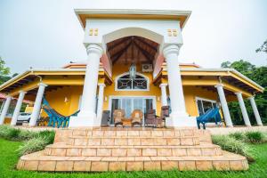 a yellow house with a staircase in front of it at Luxe - 5 Lakeview Villas - Weddings - Retreats - AC - Pool - Hot Tub - Sleeps 25 in Aguacate