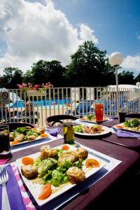 a table with plates of food on it with a pool at Camping Officiel Siblu Les Pierres Couchees in Saint-Brevin-les-Pins