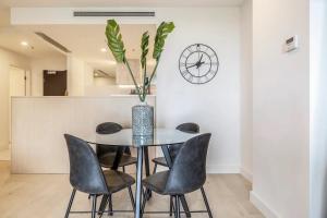 a dining room with a table and chairs and a clock at Lavish Condo Prestigious St Kilda Rd Boulevard in Melbourne