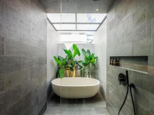 a bathroom with a tub with a plant in it at Tannari Villa Ubud in Ubud