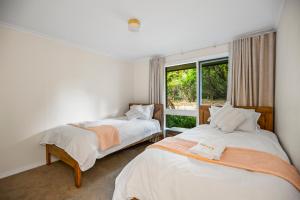 two beds in a room with a window at StayAU The Homestead 4BR Spacious Nature Retreat in Badger Creek +23 photos