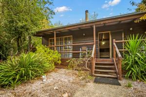 una baita di tronchi con una scala che conduce alla porta d'ingresso di StayAU Cedar Lodge 3BR Quaint Countryside Cottage a Badger Creek