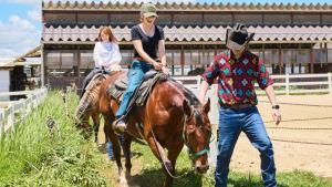阿苏市庭院牧场酒店的一名女子骑在马背上，旁边还有一名男子