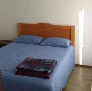 a bedroom with a bed with blue sheets and blue pillows at Cabañas de Los Trigales in Guanaqueros