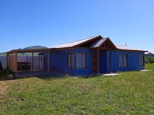 a blue house sitting on top of a grass field at Cabañas de Los Trigales in Guanaqueros