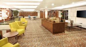 a lobby with a library with yellow chairs and a television at Mard-inn Hotel in Istanbul