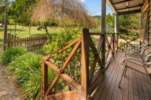 un portico in legno con due sedie e una recinzione di StayAU Birchwood Cottage 2BR Yarra Valley Cottage a Badger Creek