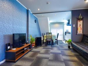 un salon avec un canapé et une télévision dans l'établissement F House 青い海, à Osaka