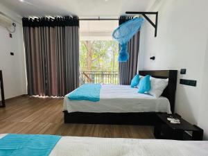 a bedroom with two beds and a large window at Residence Safari Udawalawa in Udawalawe