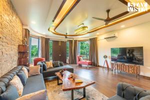 a living room with a couch and a brick wall at StayVista at Wandering Vines 4BHK with FREE Breakfast ,Indoor Pool in Delhi Sohna in Sohna
