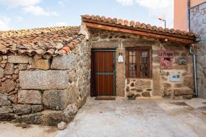 an old stone house with a red door at La Fragua in Villar de Corneja