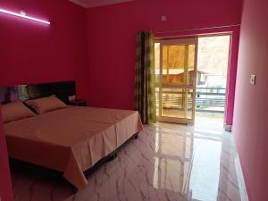 a red bedroom with a bed and a sliding glass door at Welcome Home Stay & Hotel Tapovan Rishikesh in Rishīkesh
