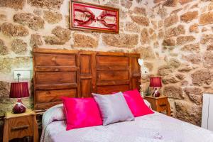 a bedroom with a bed with two pink pillows at La Fragua in Villar de Corneja