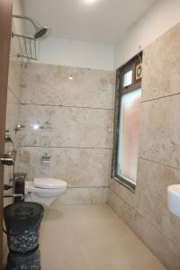 a bathroom with a toilet and a sink and a window at THE GRAND KRISHNA ROOMS Patan in Pātan +19 photos