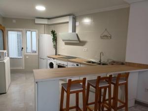 a kitchen with three bar stools and a counter top at Piso Turístico Arévalo in Arévalo
