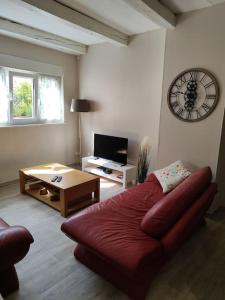 a living room with a red couch and a clock on the wall at Le sceycolais Appartement spacieux avec terrasse in Scey-sur-Saône-et-Saint-Albin