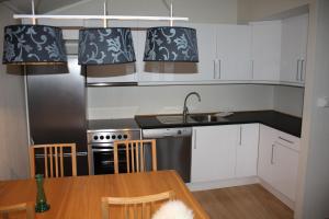 a kitchen with white cabinets and a table with a sink at Bortelid Booking in Tjaldal