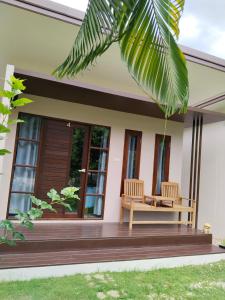 a house with two chairs on the front porch at เดอะนิรันดร์ เกสท์เฮ้าส์กาญจนบุรี in Ban Chuk Yai Yuan