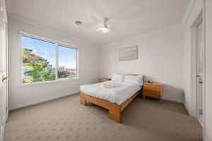 Un dormitorio blanco con una cama y una ventana. en Doncaster East Home walking to shops restaurants, en Doncaster East