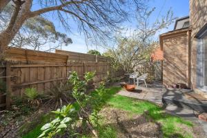un patio trasero con una valla de madera y un banco en Doncaster East Home walking to shops restaurants, en Doncaster East
