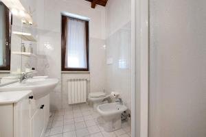 een witte badkamer met een toilet en een wastafel bij Miralago Marone Holiday House in Marone +13 foto's