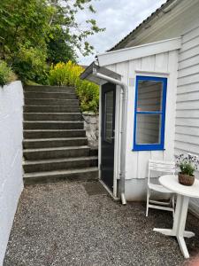 un edificio bianco con una porta blu e un tavolo di Lite hus med egen inngang - Sentral beliggenhet a Haugesund