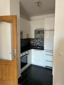 eine Küche mit weißen Schränken und schwarzem Fliesenboden in der Unterkunft Apartman SARA in Sarajevo + 5 Fotos