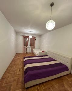 ein Schlafzimmer mit einem Bett mit einer lila Decke in der Unterkunft Apartman SARA in Sarajevo
