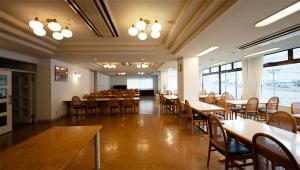 una sala da pranzo con tavoli, sedie e finestre di ビューリゾートインとみや a Yuzawa