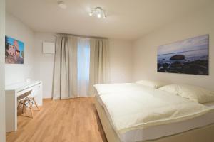 ニュルンベルクにあるPremium Apartments Thommenの白いベッドルーム(ベッド1台、デスク付)