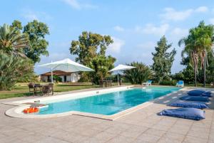 een zwembad met blauwe kussens en parasols bij Tenuta Badessa in Casalabate