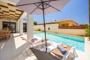 un patio con sombrilla y sillas y una piscina en Villa Petra, en Trapezaki