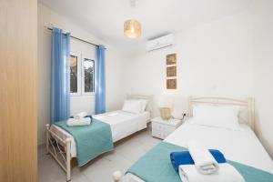 two beds in a white room with blue curtains at Villa Eleftheria in Spartià +29 photos